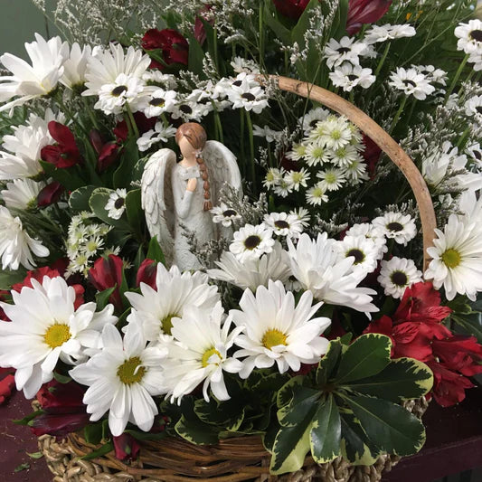 Angel in a basket with fresh cut flowers.